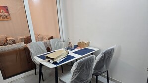Comedor con una mesa dispuesta para cuatro personas, cubierta con un camino de mesa azul y rodeada de sillas protegidas con plástico.