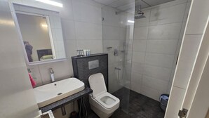 Un baño moderno con lavamanos blanco, inodoro y ducha.