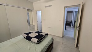 Un dormitorio con cama, ventilador de techo, armario y baño visible a través de una puerta abierta.