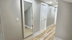 Un pasillo con piso de madera, paredes blancas y dos puertas blancas.