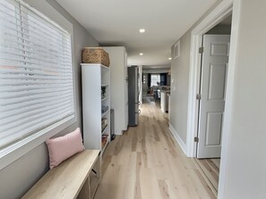 A hallway with a bench, a white cabinet, and a door leading to another room. - Pink House - Downtown & 7 Mins to Cedar Point (Sandusky)
