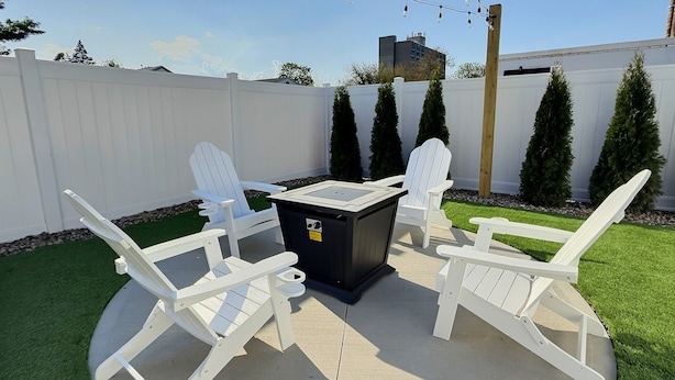 Un patio al aire libre con una mesa chimenea y cuatro sillas Adirondack.