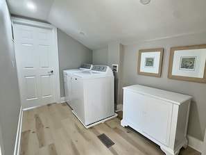 Une buanderie équipée d’un lave-linge, d’un sèche-linge, d’un meuble de rangement et d’une porte.