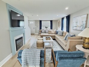 A living room with a fireplace, a sofa set, a coffee table, and a television. - Pink House - Downtown & 7 Mins to Cedar Point (Sandusky)