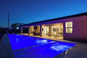Uma casa moderna com piscina, área de estar externa e interior bem iluminado.