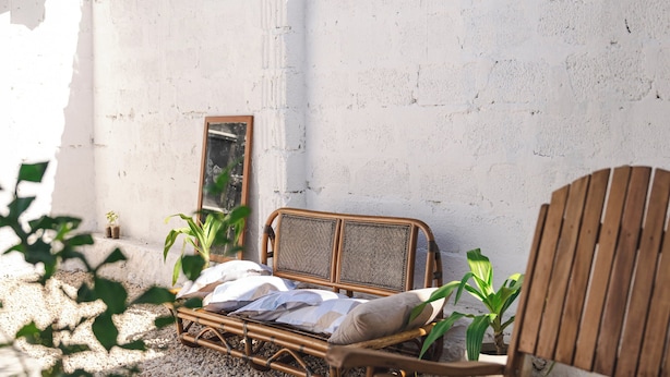 A rustic outdoor seating area with a wicker chair, a wooden table, and a potted plant. - Hiliki Holiday Home Paje - by Liv Zanzibar (Paje)
