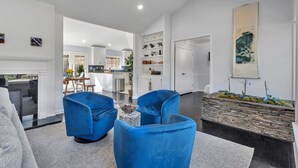 Een moderne woonkamer met blauwe stoelen, een stenen plantenbak en een keuken op de achtergrond.