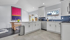 Een moderne keuken met witte kasten, een roestvrijstalen vaatwasser en een inbouwoven.