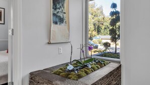 Een kamer met een tafel van natuursteen, een schilderij aan de muur en uitzicht buiten door een raam.
