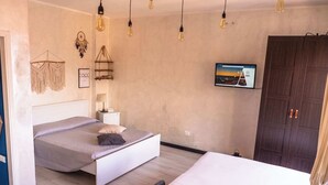 Un dormitorio con dos camas, un televisor montado en la pared y un armario.