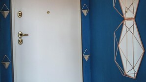 Una habitación con puerta blanca, paredes azules, decoración mural geométrica e iluminación.