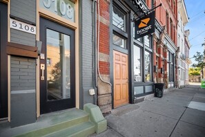 A building with a black door, a brick facade, and a sign for 'boost mobile'. - Central, Lawrenceville @ 1A Bright Studio with Free Street Parking (Pittsburgh)