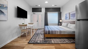 Een moderne slaapkamer met een bed, een televisie, een bureau en een koelkast.