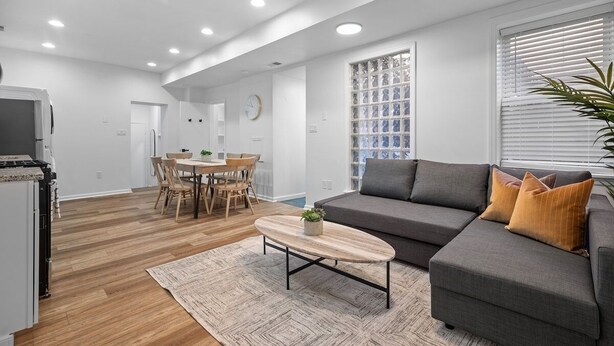 Ein modernes Wohnzimmer mit einem grauen Sofa, einem Couchtisch und einem Essbereich mit Holzkohle und einem weißen Tisch.