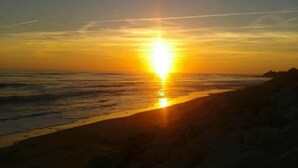 Een zonsondergang boven een strand met een heldere lucht.