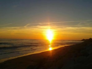 A sunset over a beach with a clear sky.