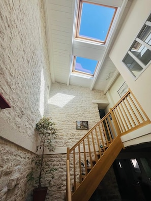 A multi-level interior with a staircase, stone walls, and skylights.