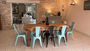 Een eetgedeelte met een houten tafel en stoelen, een stenen muur en uitzicht op een andere kamer.