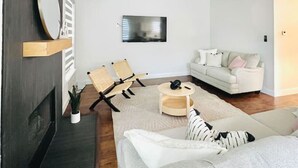 A modern living room with a grey sofa, a white armchair, a wooden coffee table, and a ceiling fan. - Pickleball + Pool + Bkyd Oasis + Centrally Located (Frisco)