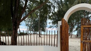 A gated entrance with a white archway and a wooden fence. - 5 BED Beach front Villa Paje (Paje)