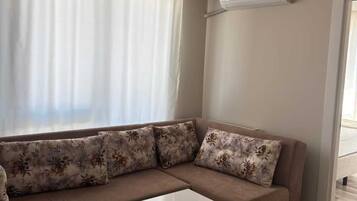Un soggiorno con un divano color beige, cuscini floreali, un tavolino da caffè bianco e un tappeto decorato.