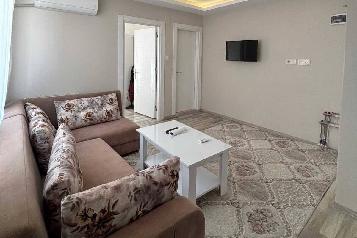 Un saló modern amb un sofà modular, una taula petita blanca i una catifes amb dibuixos.