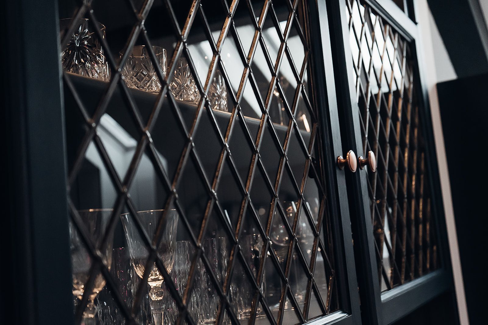 Ein Detailaufnahme eines schwarzen Metallgitters mit diamantförmigen Mustern, vermutlich Teil eines Tür- oder Fensterrahmens.