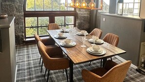 Ein Essbereich mit einem großen Tisch, gedeckt für sechs Personen, umgeben von Steinwänden und großen Fenstern.