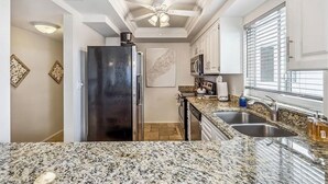 A kitchen with granite countertops, stainless steel appliances, and white cabinetry. - Beautiful Sand Caper 408. 2B/2B condo steps from the Gulf. AMAZING Sunsets (Fort Myers Beach)