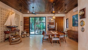 Un comedor amplio con una mesa y sillas de madera, una decoración con un velero y vistas al exterior a través de puertas correderas grandes.
