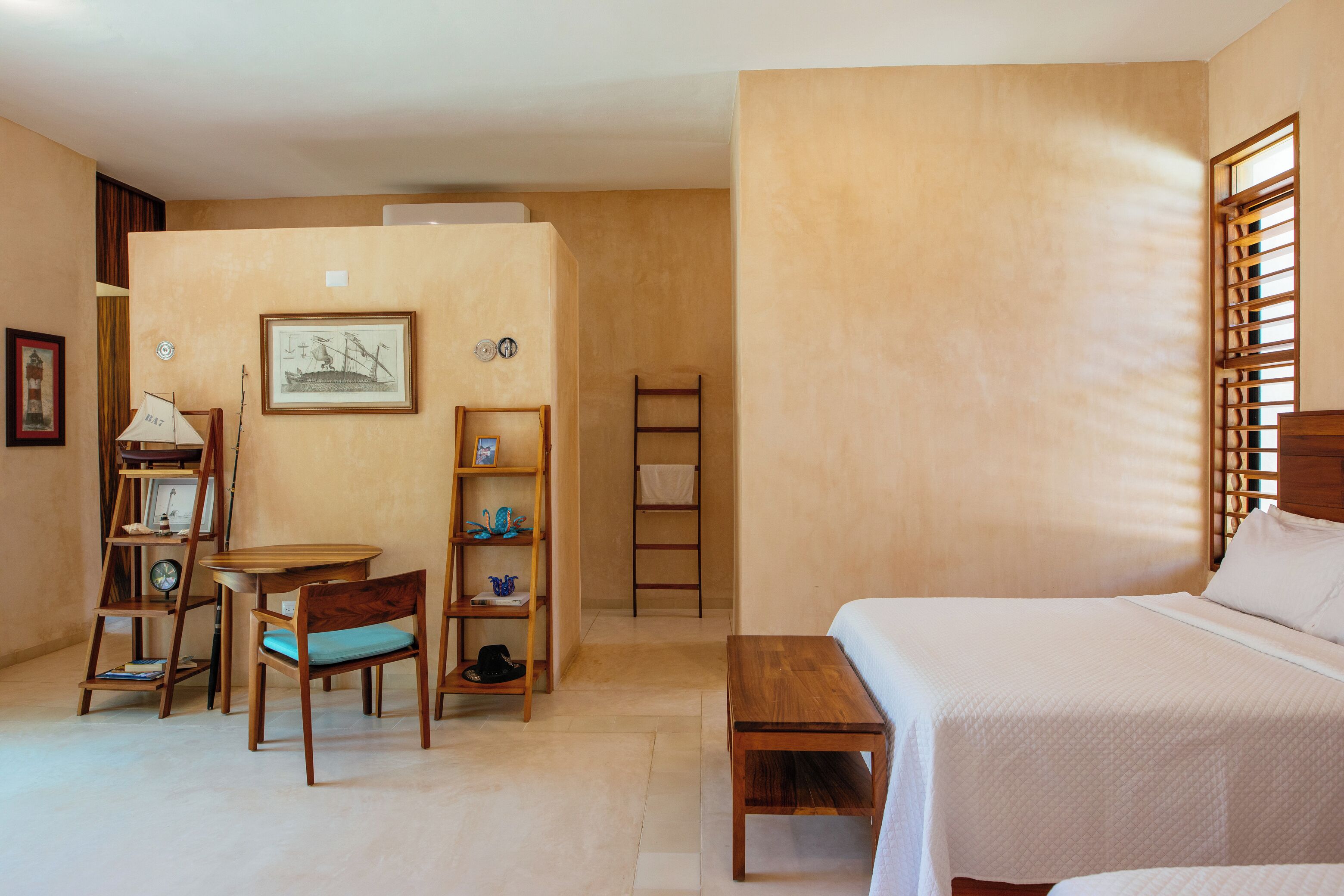 A bedroom with a bed, a desk with a chair, a wooden ladder, and shelves with decorative items.