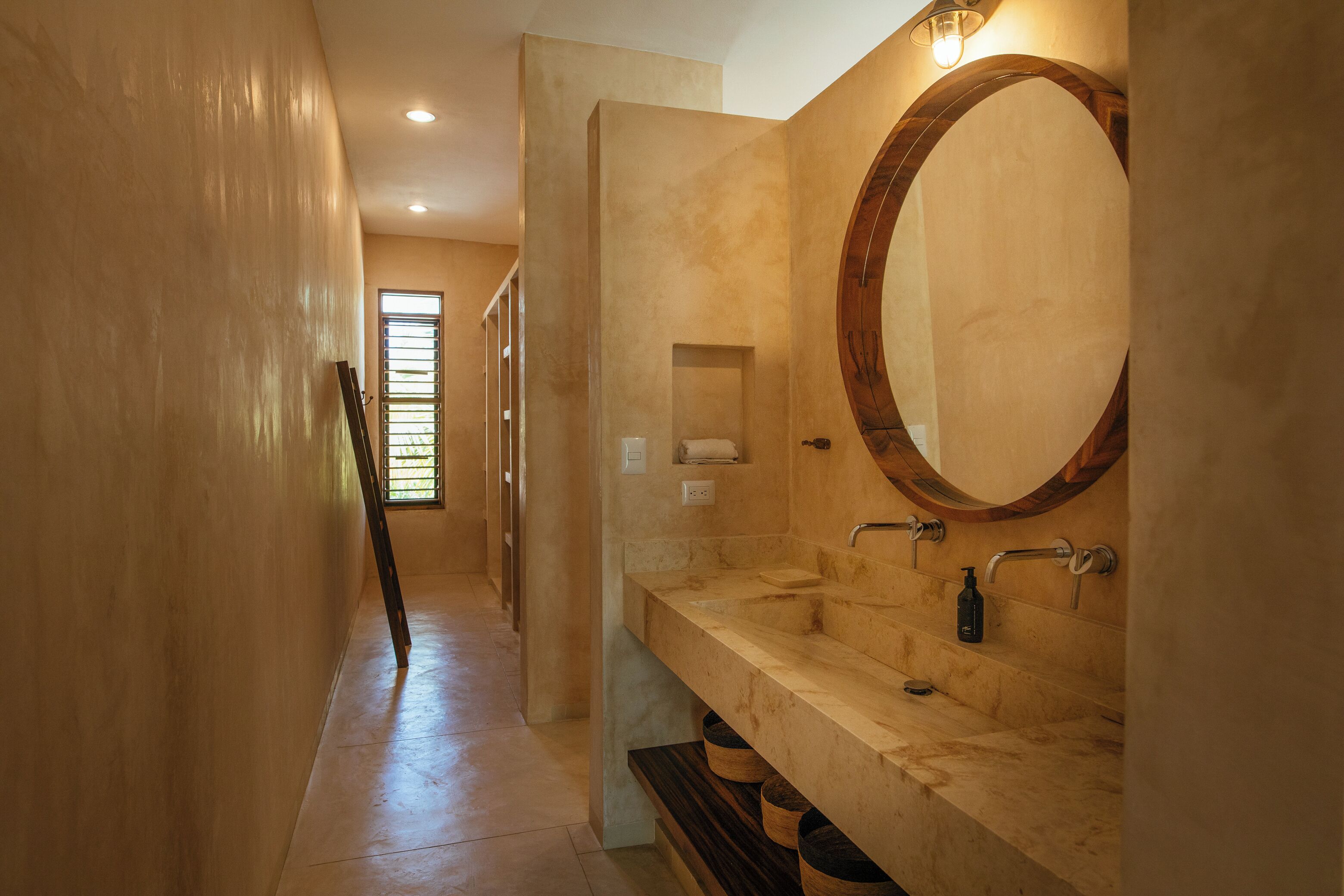 A modern bathroom with a large mirror, dual sinks, and a wooden vanity.