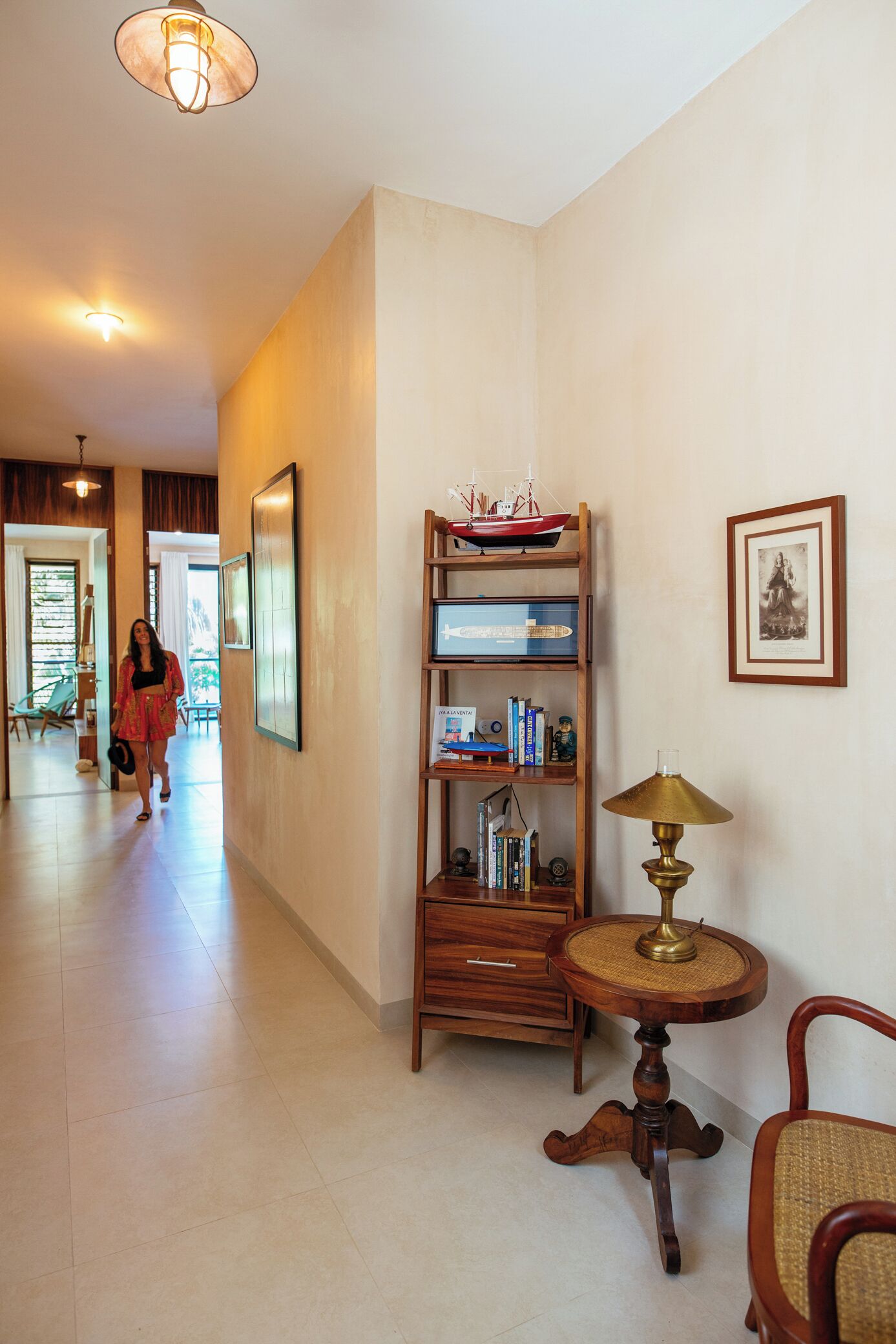 A hallway with a wooden bookshelf, a brass lamp, and a framed picture on the wall.