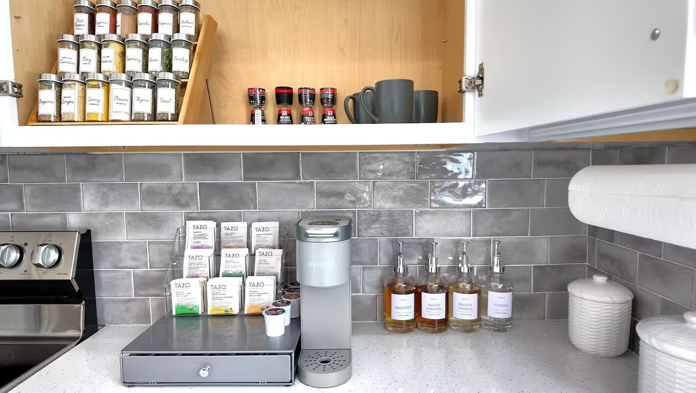 A kitchen with a stainless steel range, a coffee machine, and various condiments and spices.