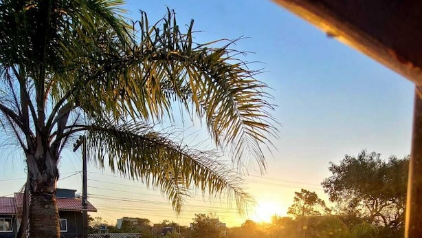 Een uitzicht op een woongebied met een zwembad, palmbomen en huizen tijdens de zonsondergang.