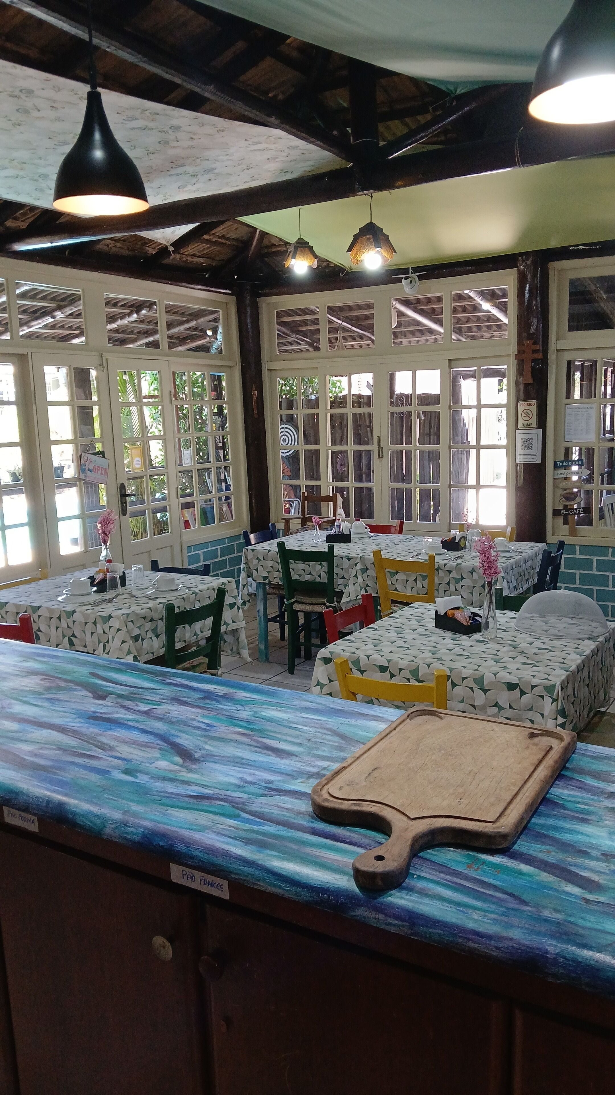 A restaurant interior with multiple tables, chairs, and hanging pendant lights.