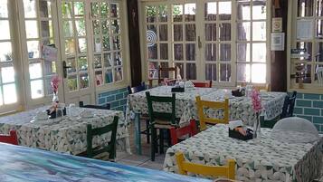 A restaurant interior with multiple tables, chairs, and hanging pendant lights.