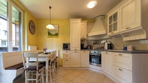 Una cucina con mobili bianchi, un tavolo da pranzo con sedie, un forno a microonde e un fornello.