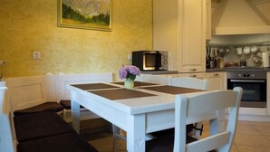 Una cucina con mobili bianchi, un forno a microonde e un tavolo da pranzo con sedie.