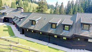 Un edificio moderno con numerose finestre a lucernario e un tetto spiovente, circondato da un'area recintata e vegetazione.