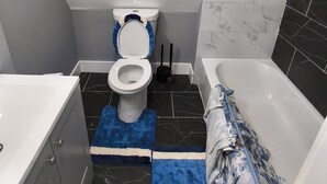 Pieni kylpyhuone, jossa on wc, bidee ja kylpyamme.
