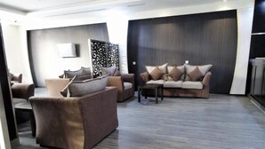 A modern living room with a sofa set, a coffee table, and a decorative wall panel. - al sahafah gate hotel (Riyadh)