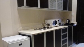 A compact kitchen with a refrigerator, microwave, kettle, and a sink. - al sahafah gate hotel (Riyadh)