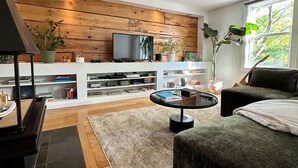 Un salon moderne avec un mur revêtu de panneaux en bois, un téléviseur à écran plat, une table basse et un canapé.