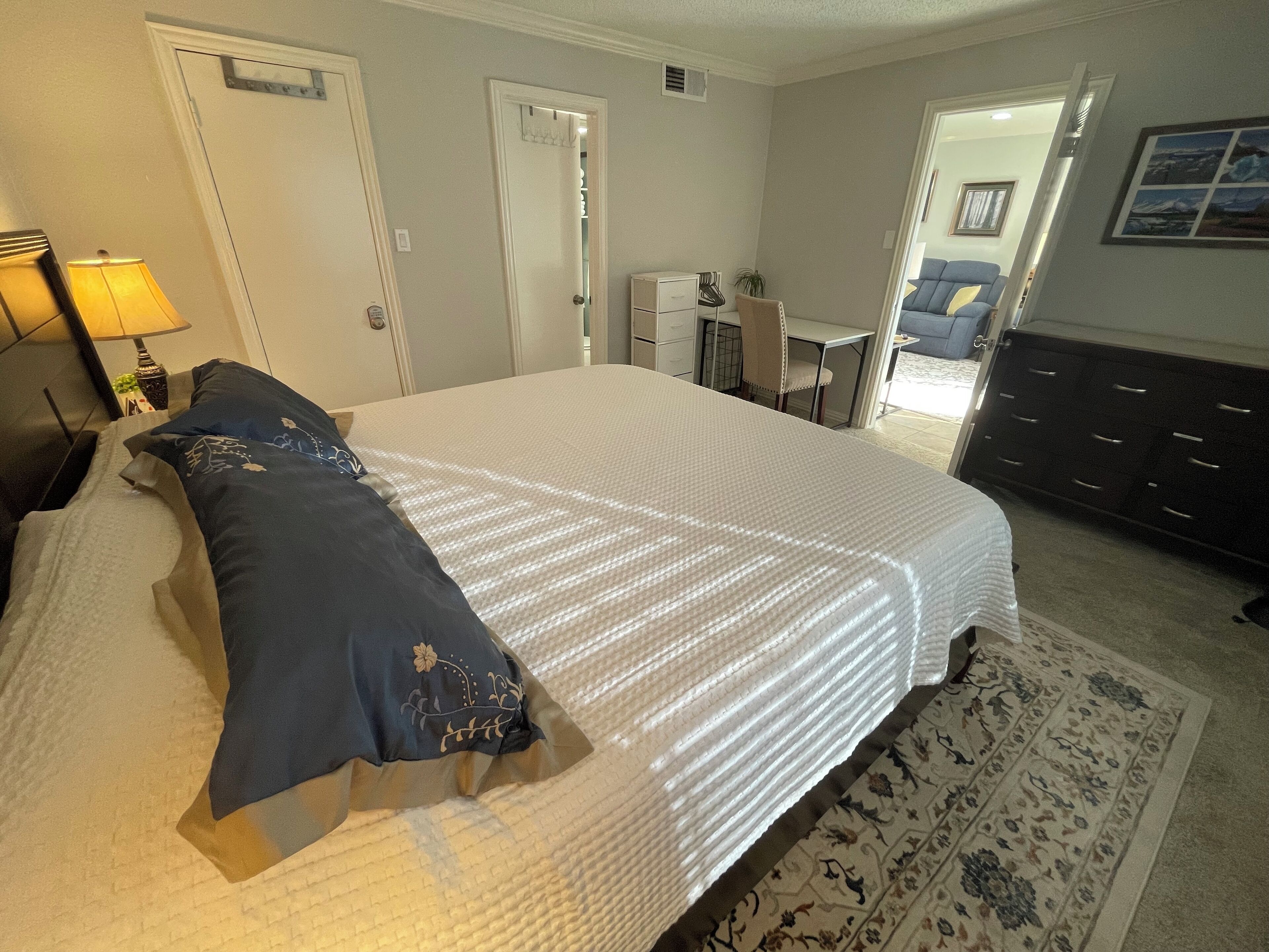 Une chambre bien rangée, avec un grand lit, un bureau et une chaise au fond de la pièce.