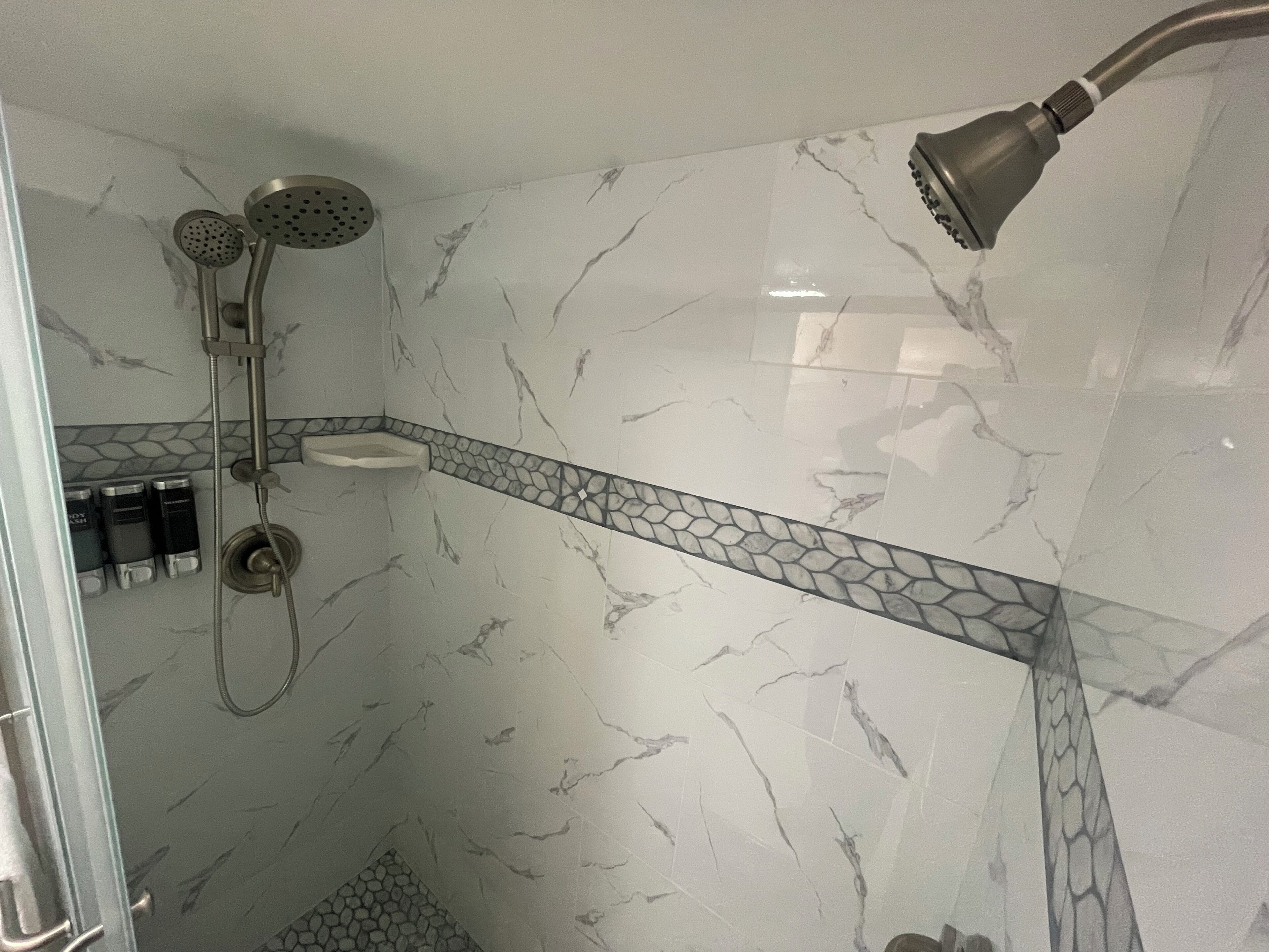 Une salle de bain équipée d’une douche, d’un lavabo et d’un distributeur de savon.