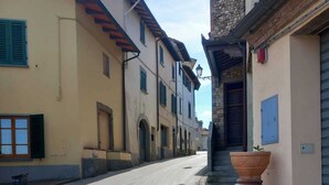 A narrow street with buildings on either side, featuring arched doorways and traditional architecture.