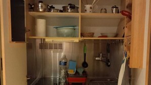 A compact kitchen with a refrigerator, sink, and various storage containers.