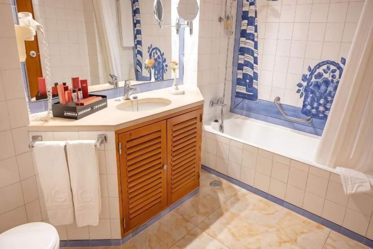 A bathroom with a sink, mirror, vanity, and bathtub.