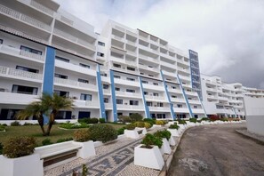 A multi-story hotel with balconies, a paved walkway, and landscaped areas. - Grand Muthu Oura View Beach Club (Albufeira)